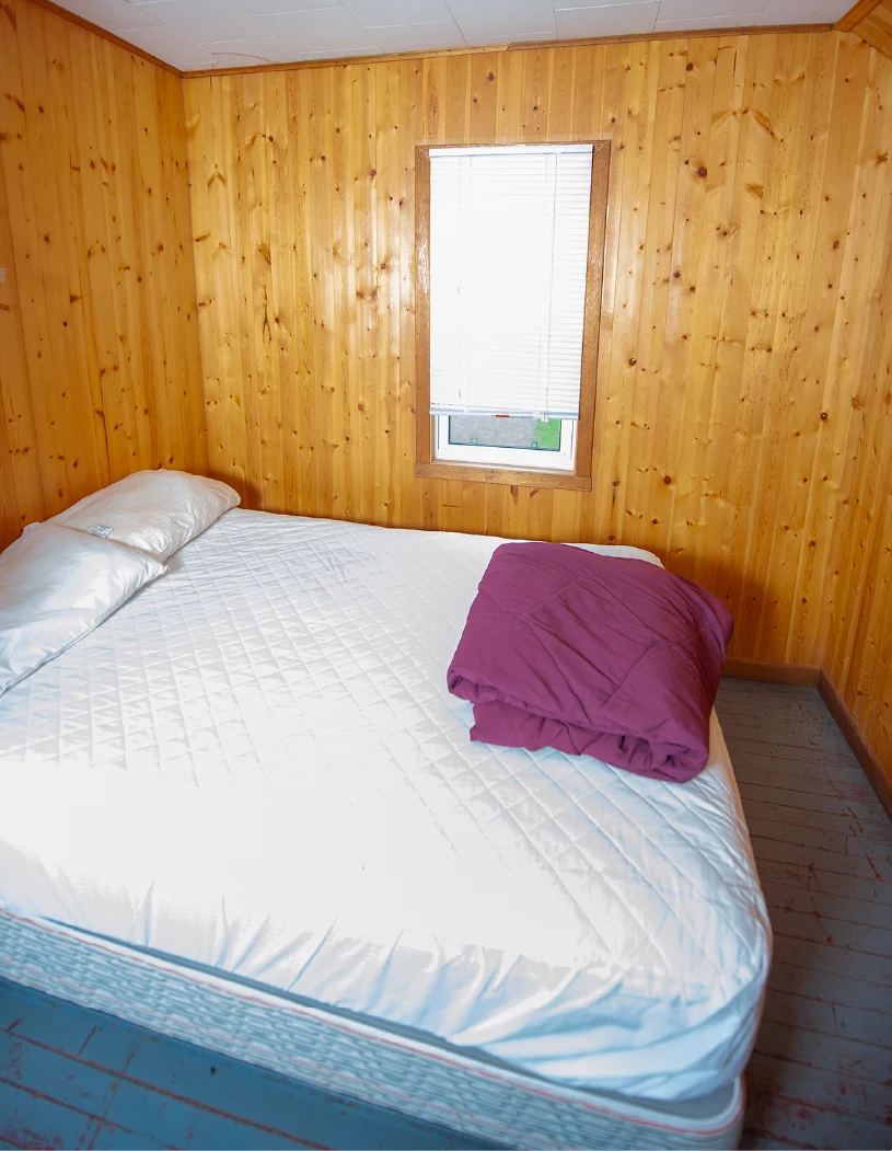 Pigeon Lake Resort Cottage five, bedroom with queen bed, wood-paneled walls, window.
